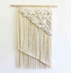 a wall hanging with white yarn and wooden sticks