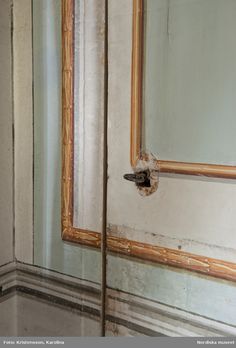 an old mirror with peeling paint on the wall and wood trimmings around it