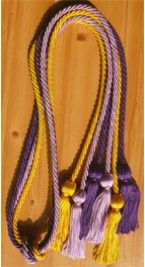 three ropes with tassels are on a wooden surface