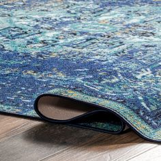 an area rug with blue and green colors on the wooden floor, close up view