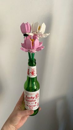 a person is holding a bottle with flowers in it and there is a paper flower sticking out of the top