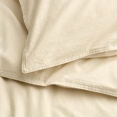 an unmade bed with white sheets and pillows