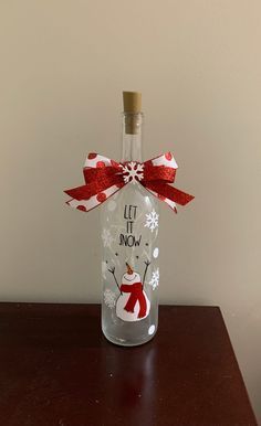 a wine bottle with a snowman on it sitting on top of a wooden table