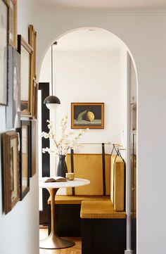 an archway leading to a living room with yellow chairs and white table in the center