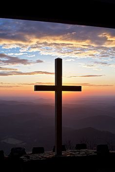 a cross on top of a hill at sunset