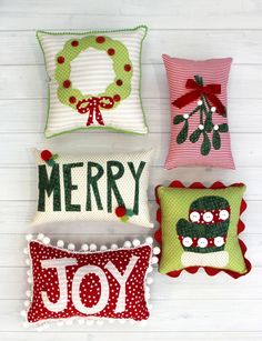 four christmas pillows with the words merry and joy on them, all in different colors