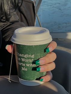 a woman's hand holding a coffee cup with green nail polish on it and the words changing the world starts with me