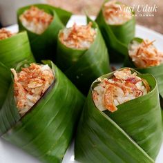 some food is wrapped in green leaves on a plate