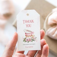 a person holding up a thank you tag with a tea cup on it and pink flowers