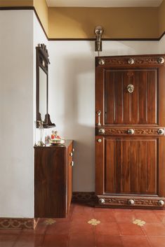 a wooden door is open in a room with red tile flooring and white walls