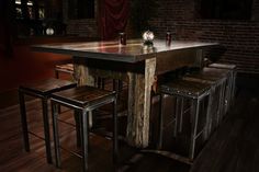 a wooden table with four stools next to it on a hard wood floor in a dimly lit room