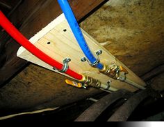 two red, white and blue pipes are attached to a wooden structure with metal fittings