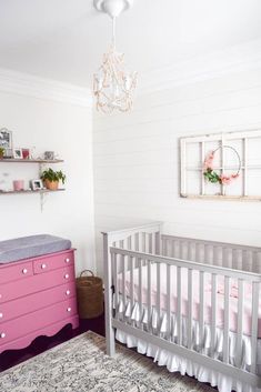 a baby's room with a pink dresser and crib in the corner next to it