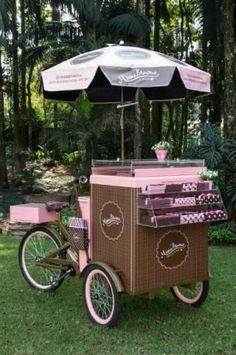 a pink ice cream cart with an umbrella over it's top in the grass