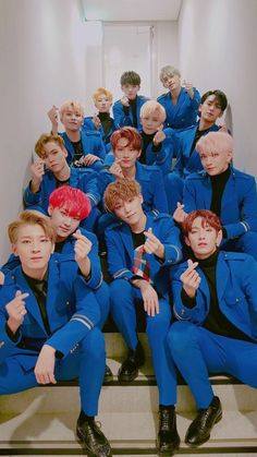 a group of young men sitting on top of stairs in blue suits and black shoes