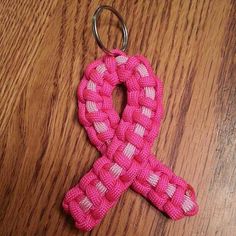 a pink and white ribbon shaped keychain sitting on top of a wooden table