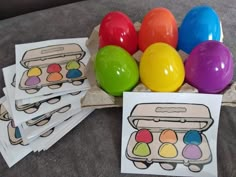 an egg carton filled with colored eggs next to coloring pages