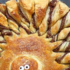 a smiley face made out of bread on top of a pan filled with pastries