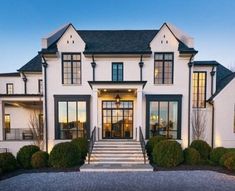 a large white house with lots of windows and steps leading up to the front door