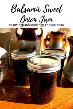 three jars filled with jam sitting on top of a wooden table next to vases