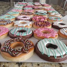 a table topped with lots of donuts covered in frosting and sprinkles