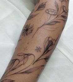 a woman's arm with flowers and leaves on it