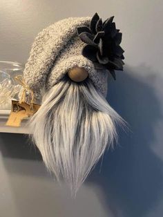 a hat with long white hair and a black flower on it is sitting on a shelf