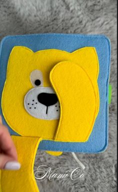 someone is holding up a yellow and blue felt toy with a dog's face on it