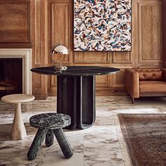 a table with two stools in front of it and a painting on the wall