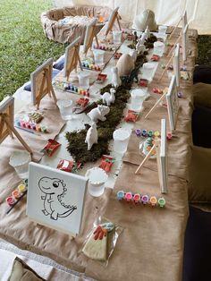 a long table covered in lots of cups and bowls filled with dirt sitting on top of a grass covered field