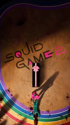 a person standing in front of a wall with the word squid game painted on it