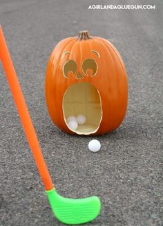 an orange pumpkin with a hole in it and a green golf putter