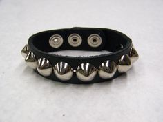 a black leather bracelet with silver spikes and studs on the end, sitting on a white surface