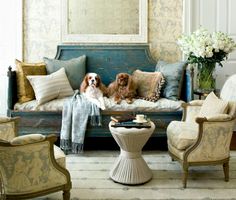 two dogs sitting on a couch in a living room with blue and white decor,