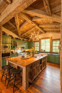 a large kitchen with wooden floors and green cabinets, an island in the middle is surrounded by stools