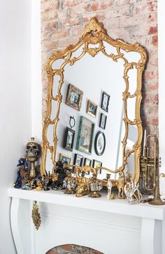 a fireplace with a mirror and many pictures on it