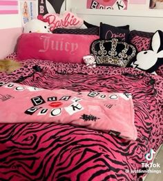 a bed with pink and black zebra print comforter, pillows and a crown on it