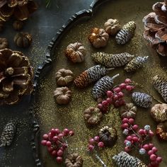 pine cones, berries and other decorations on a platter with gold flecks