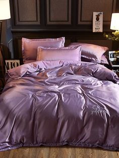 a bed with blue sheets and pillows on top of wooden flooring next to two lamps