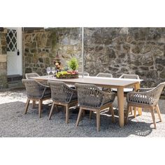 an outdoor table and chairs with an umbrella over them on graveled area next to stone wall