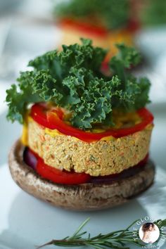 a sandwich with vegetables and sauce on it sitting on top of a white plate next to a sprig of rosemary