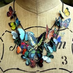 a necklace with many different colored butterflies hanging from it's center piece on a mannequin