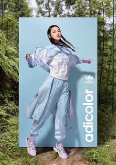 a woman standing in front of a billboard with her hands on her hips and wearing adidas sneakers