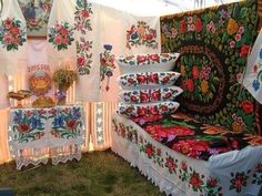 there are many different types of cloths on display at this outdoor market stall that is decorated with flowers and leaves