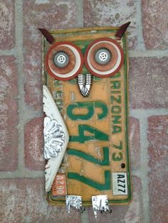 an owl made out of old license plates on a brick wall with the word arizona painted on it