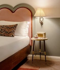 a hotel room with a bed, nightstand and lamp on the side table in front of it