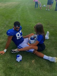 Football player in blue sitting on the grass across from girlfriend Nfl Training Camp Outfit, Nfl Wag Outfit, Football Wags Outfits, Football Games Outfit, Football Wife Outfit, Outfits For Football Games