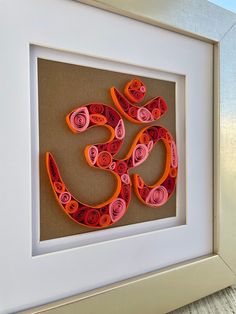 a framed art piece with an om symbol made out of rolled up paper