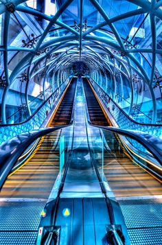 an escalator is shown in this artistic photograph with blue and yellow lighting on it