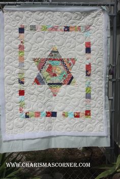 a white quilt hanging on a fence with an image of a star in the center